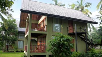 A two-story building with a balcony, a staircase, and a garden.