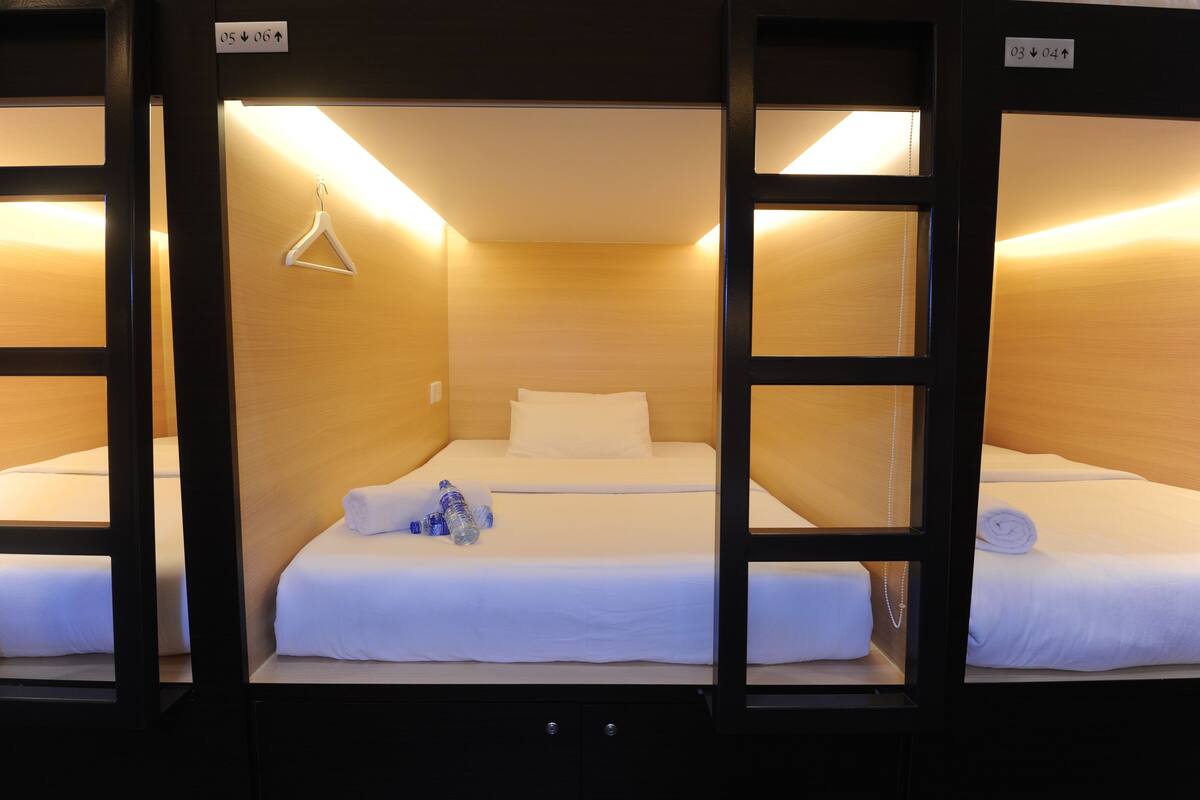 A hotel room with bunk beds, a white hanger, and a water bottle on the bed.