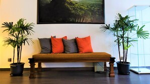 A room with a wooden bench, two potted plants, and a large landscape painting on the wall. - Star Anise Boutique Capsule (Colombo)