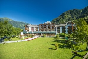 A multi-story hotel with a central courtyard, surrounded by lush greenery and mountains. - Hotel Das Gastein - including Alpentherme entrance all year and including "Gasteiner Bergbahnen" during summer season (Bad Hofgastein)
