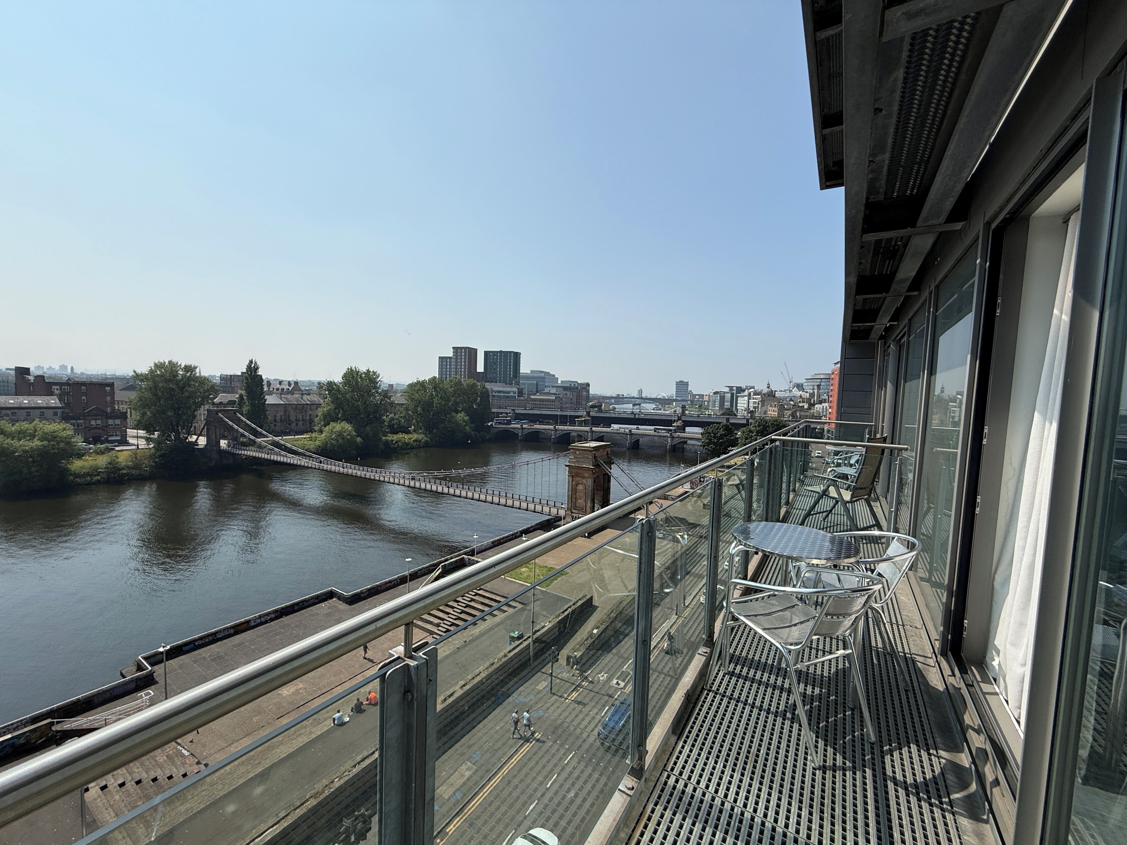 A high-rise building with a view of a river and a bridge.