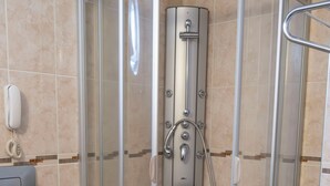 A corner shower enclosure with a glass door, a toilet, and a hand dryer on the wall. - Alkan Hotel (Marmaris)