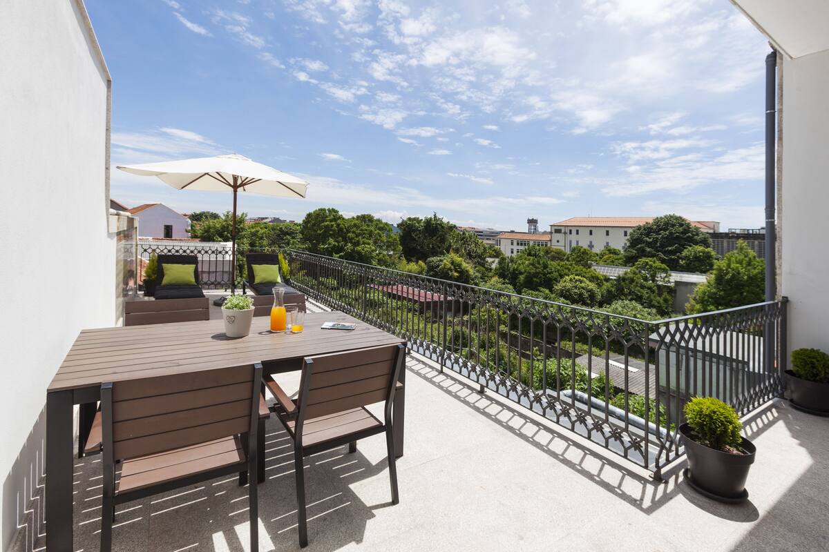 A balcony with a table, chairs, and a potted plant.