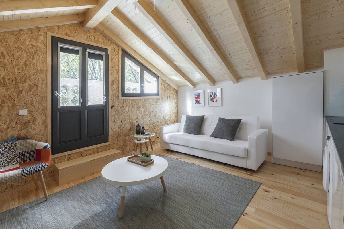 A modern interior with a white sofa, a round coffee table, and a wooden ceiling.
