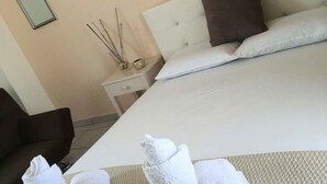Une chambre d’hôtel avec un lit, deux tables de chevet, une commode, un miroir et des serviettes sur le sol.