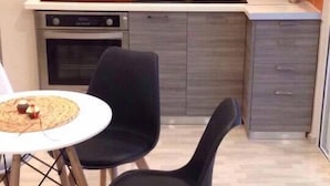 Une cuisine compacte équipée d’une cuisinière à gaz, d’un four et d’un petit coin repas avec deux chaises et une table.