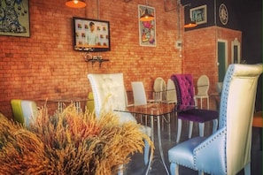 A dining area with brick walls, a television, and modern chairs. - Chaamaran Boutique Hotel (Cha-am)