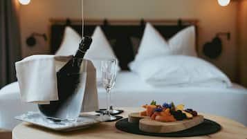A neatly arranged breakfast setting with a bottle of champagne, a glass, and a fruit platter on a round wooden table.