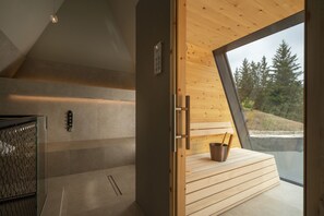 A modern interior with a wooden bench, a sauna, and a view of trees through a large window. - Olympic SPA Hotel (San Giovanni di Fassa)