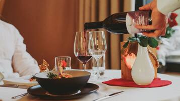 A dining table with a bowl of food, wine glasses, and a bottle being poured into one of the glasses.