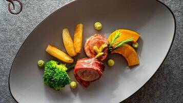 Un plato con carne, papas fritas, brócoli y una guarnición.