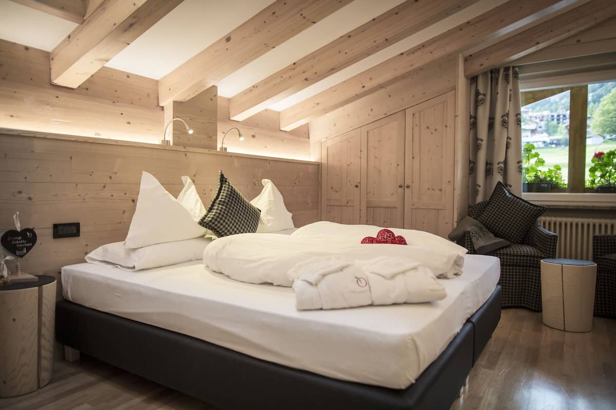 Un dormitorio con paneles de madera, una cama, mesitas de noche y vistas al exterior.