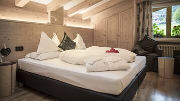 A wooden-paneled bedroom with a bed, bedside tables, and a view of greenery outside.