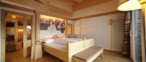 Un dormitorio con estructura de madera, una cama, un banco y un cuadro de un paisaje nevado.