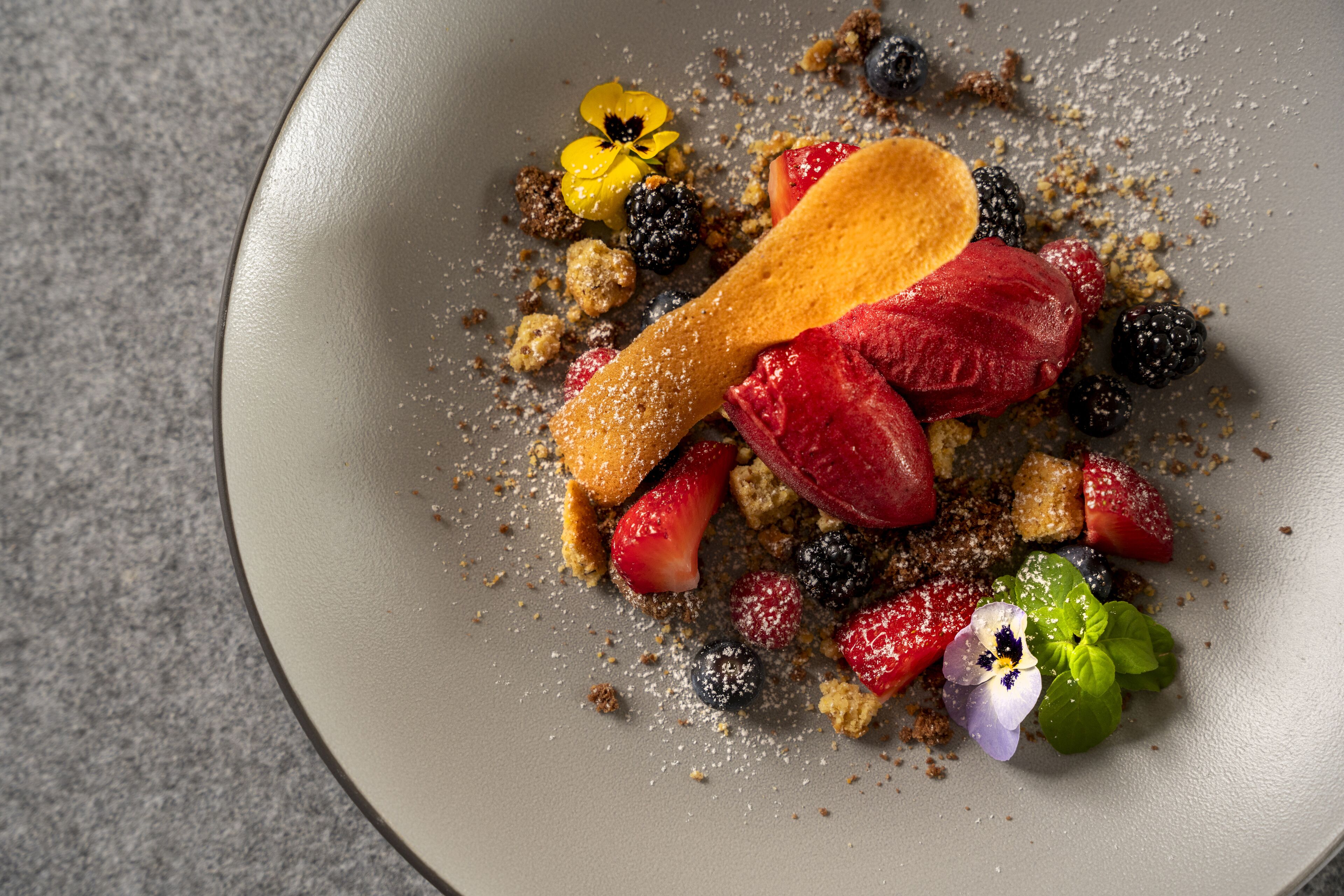 A dessert plate with various fruits and a wooden spoon.