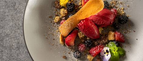 Un plato de postre con diversas frutas y una cuchara de madera.