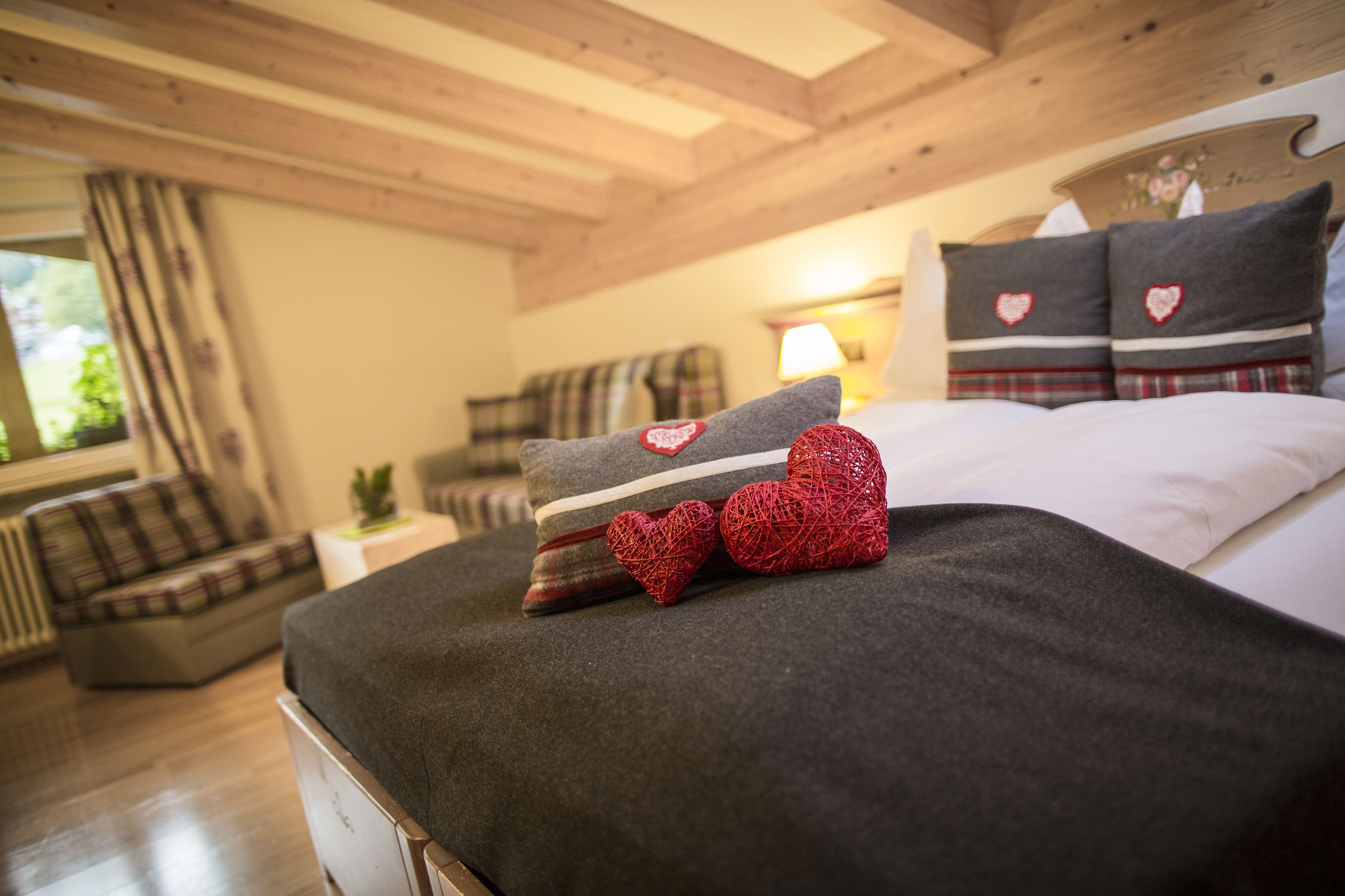 Une chambre confortable avec un plafond en bois, un lit avec une literie grise et un canapé à carreaux.