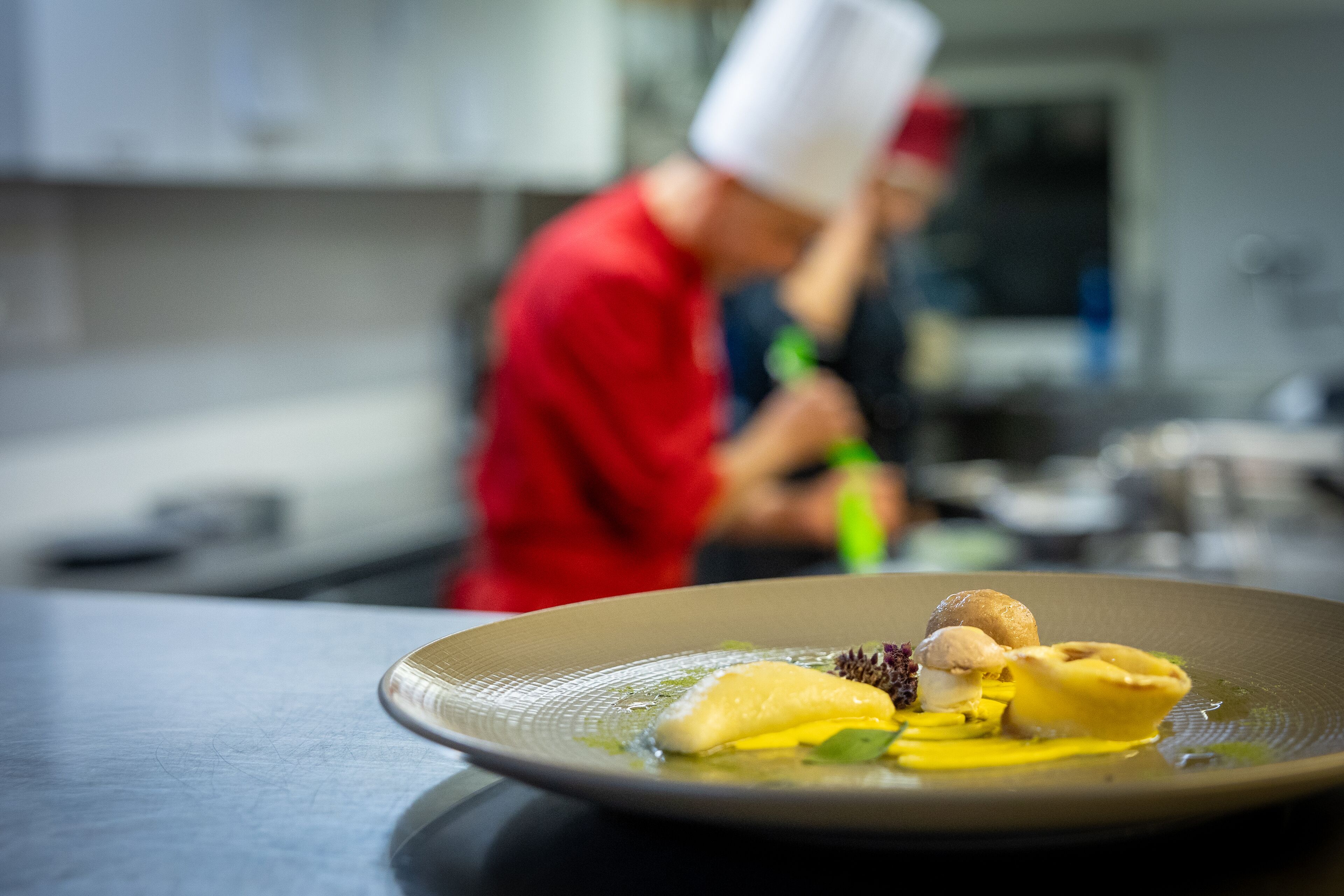 Ein Teller Essen, im Hintergrund ein Koch.