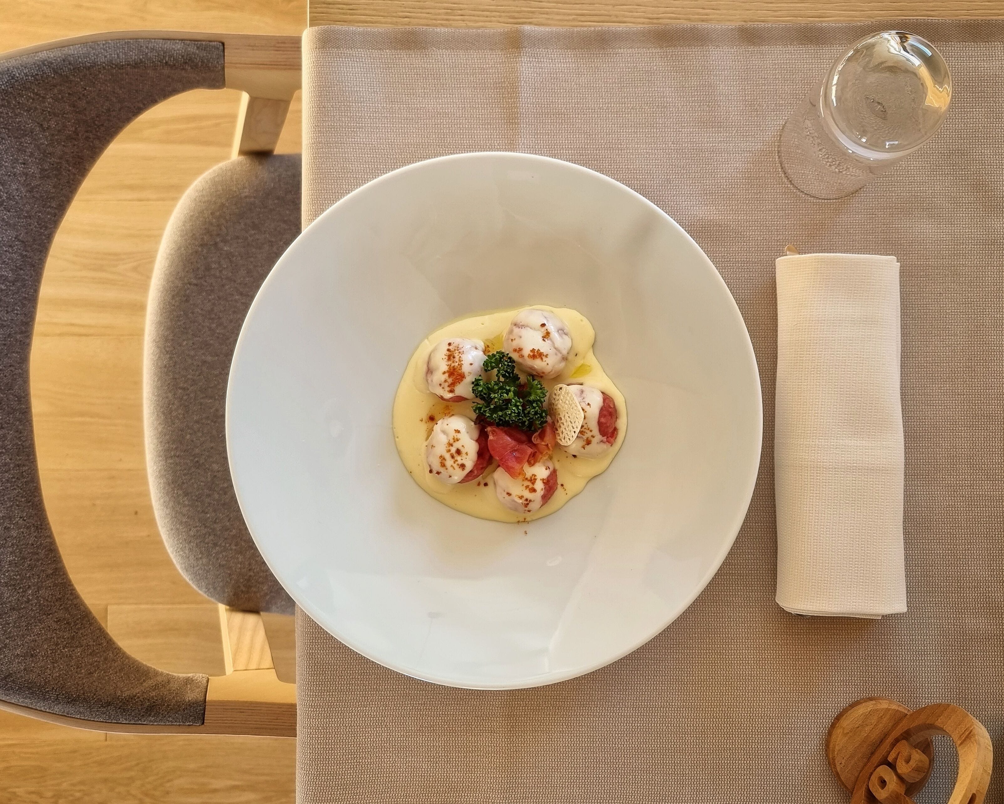 A white bowl of food on a table with a napkin and a glass of water.