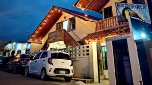 A building with a sign reading "Hostal Boquete" and a parked white car in front. - Hostal Boquete (Boquete)