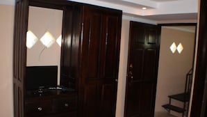 A room with a wooden wardrobe, a mirror, and a television on a dresser. - Hostal Boquete (Boquete)