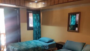 A room with two beds, a window with curtains, a mirror on the wall, and a tiled floor. - Hostal Boquete (Boquete)