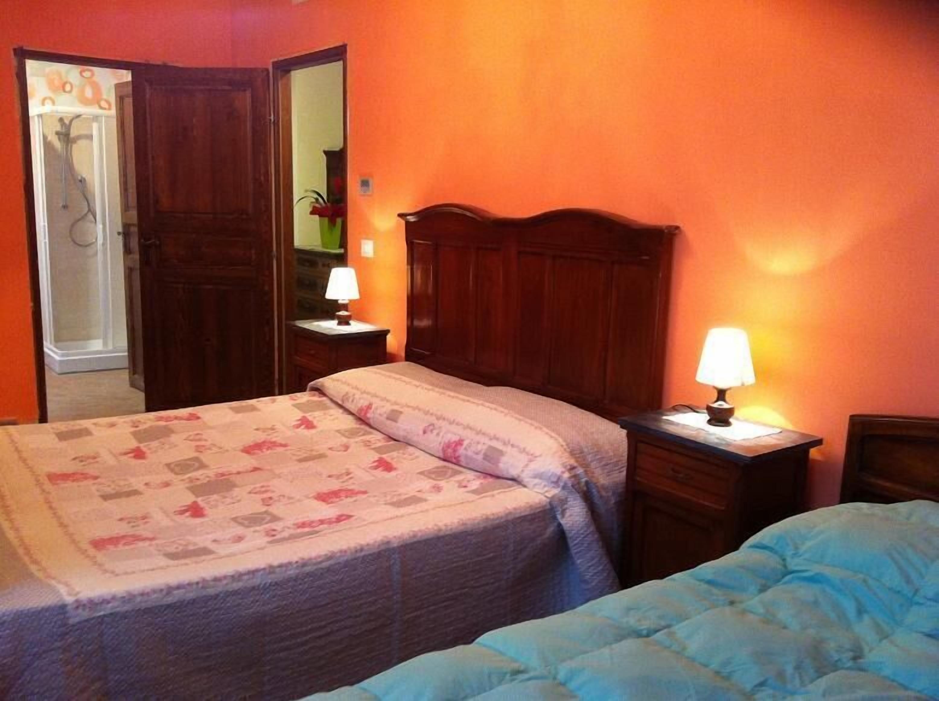 Ein Schlafzimmer mit einem Bett, zwei Nachttischen mit Lampen, einem Holzschrank und einem Spiegel.