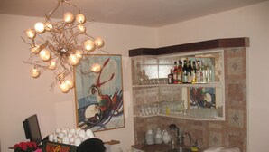 Una zona de bar con una máquina de café, un arreglo floral y una estantería con botellas y vasos.