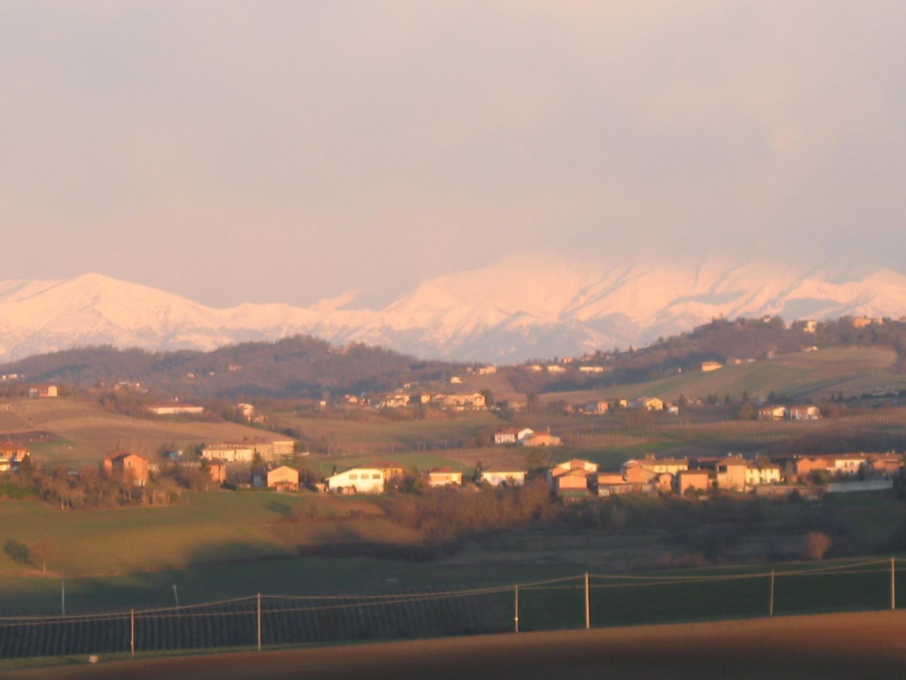 Paisatge rural amb cases i una serralada al fons.