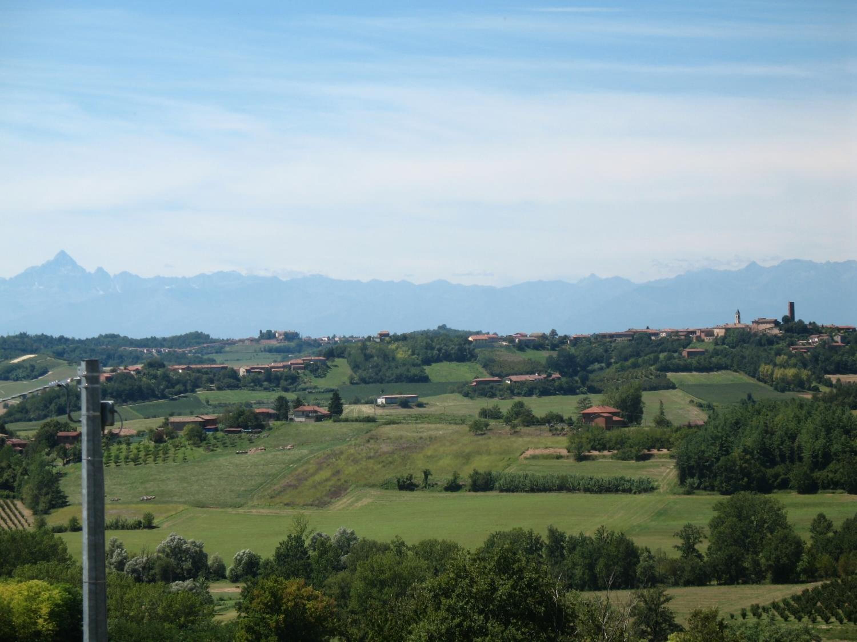 A rural landscape with rolling hills, scattered houses, and a mountain range in the background.