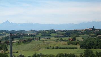 A rural landscape with rolling hills, scattered houses, and a mountain range in the background.