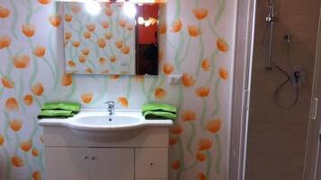 Une salle de bain avec un lavabo, un miroir et une douche.
