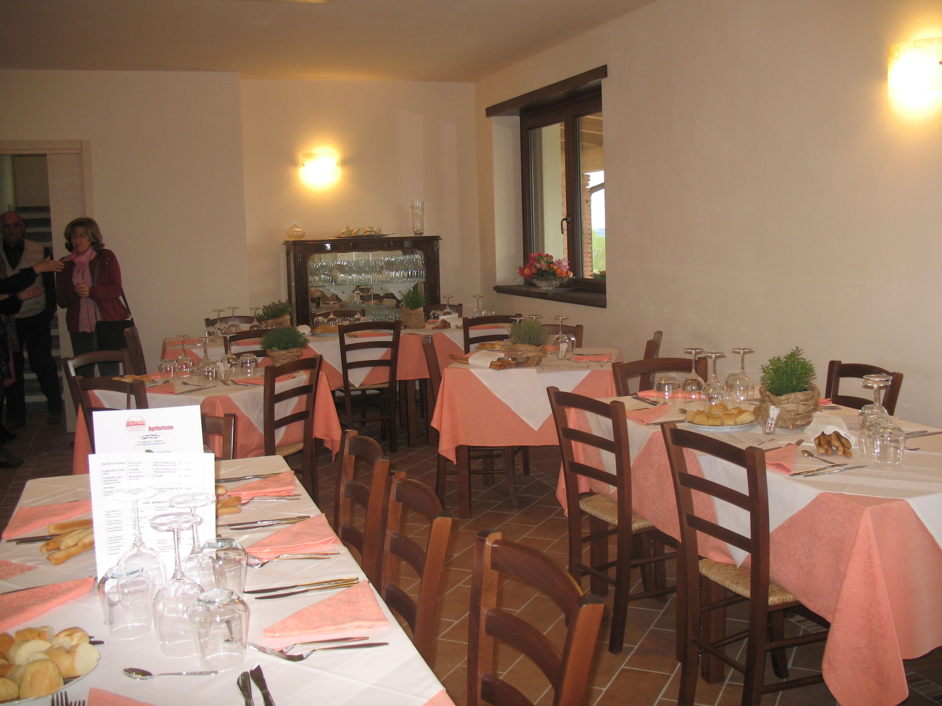 A restaurant with multiple tables set for dining, each with a menu, wine glasses, and cutlery.