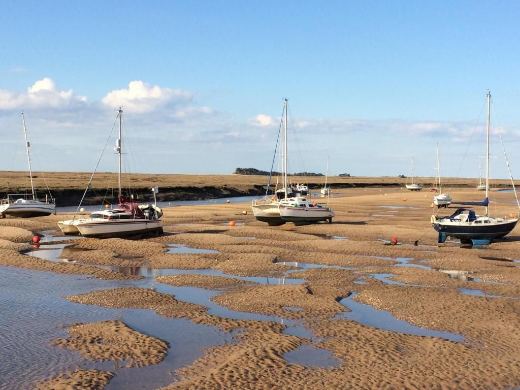 A beach with boats anchored in shallow water.