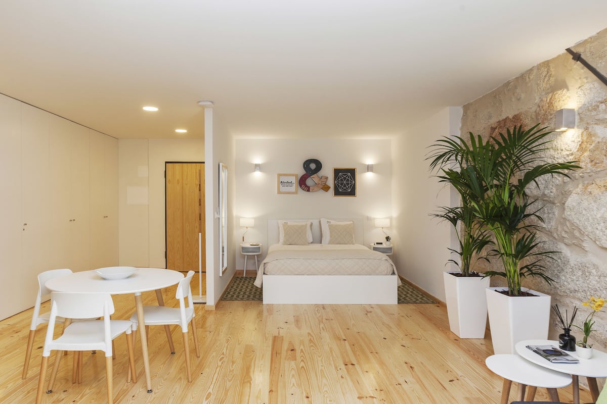 Une chambre à coucher moderne avec un lit, des tables de chevet, une table à manger ronde et des chaises.