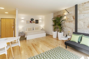 Un dormitorio moderno con cama, mesitas de noche, un sofá y una zona de comedor.
