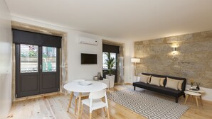 A modern living room with a white dining table, black sofa, and patterned rug. - Oporto Local Studios (Porto)