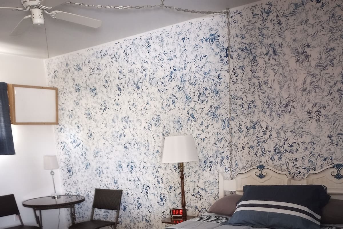 A bedroom with a bed, a desk, and a chair.