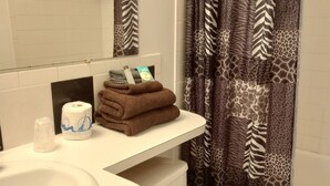 A bathroom with a white sink, toilet, and a checkered floor. There are towels and toiletries on the counter.