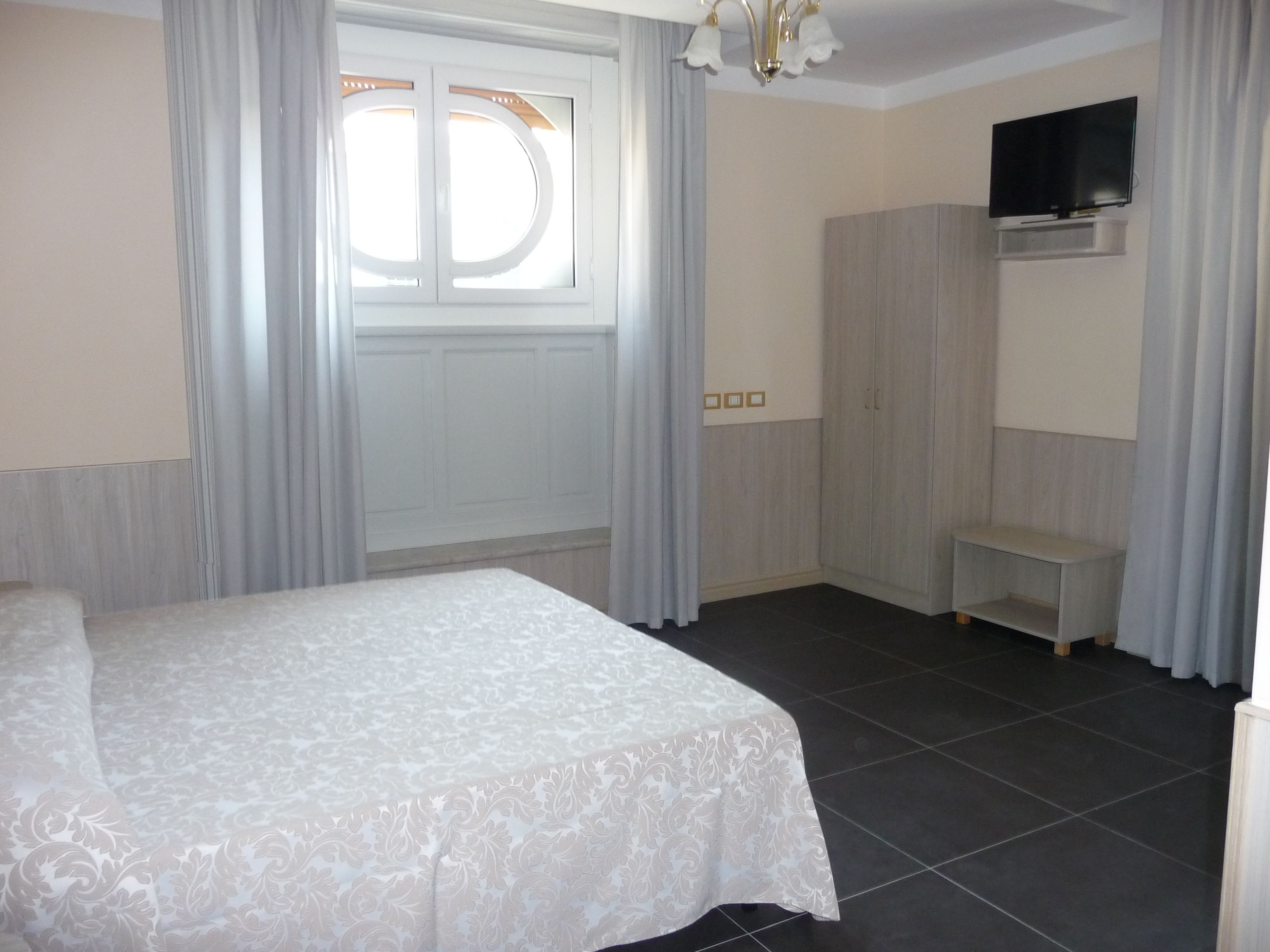 Une chambre à coucher avec un lit, un téléviseur fixé au mur et une armoire.