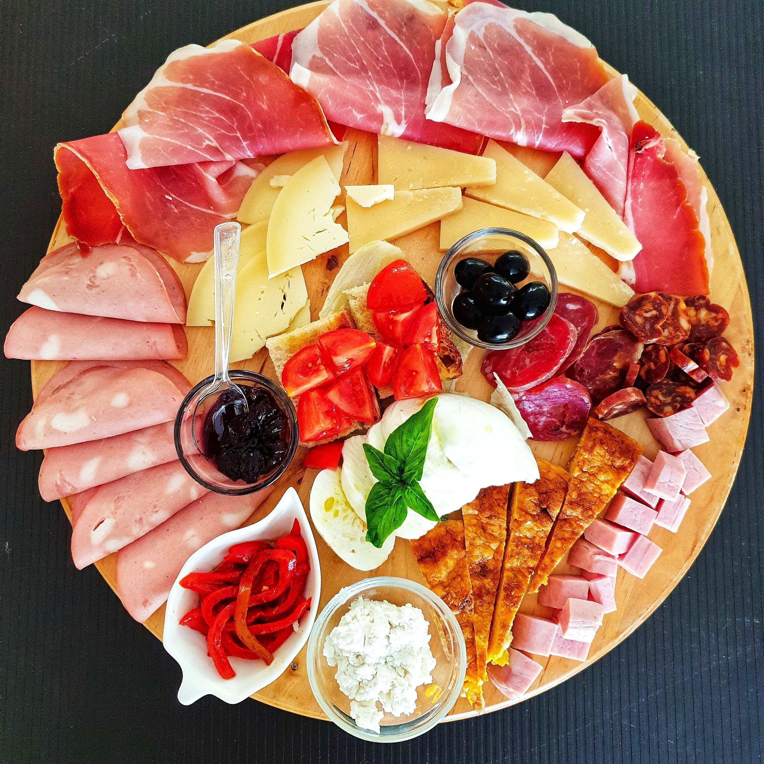 Un tagliere con salumi, formaggi e accompagnamenti vari.