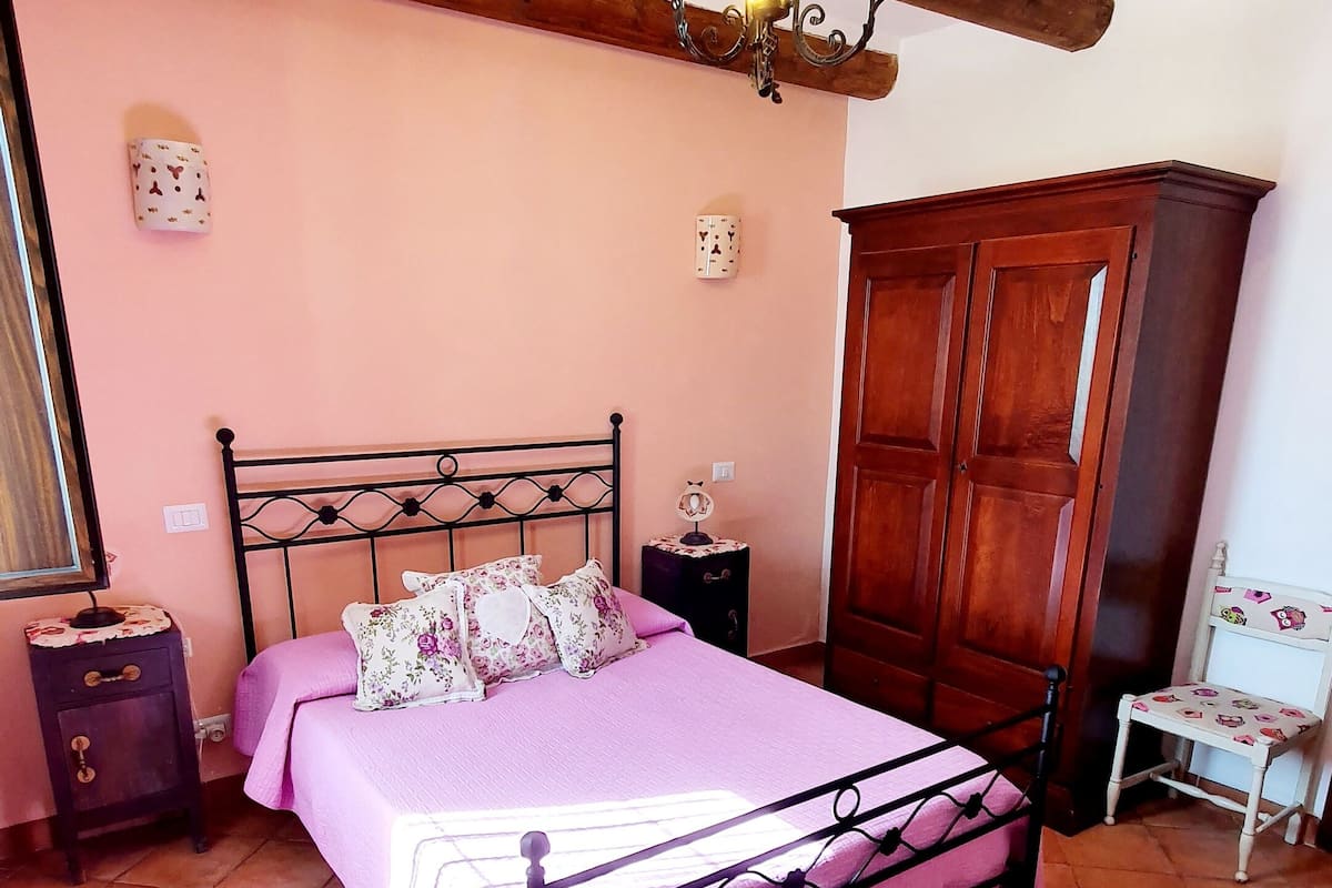 A bedroom with a bed, a nightstand, a wardrobe, and a chair.