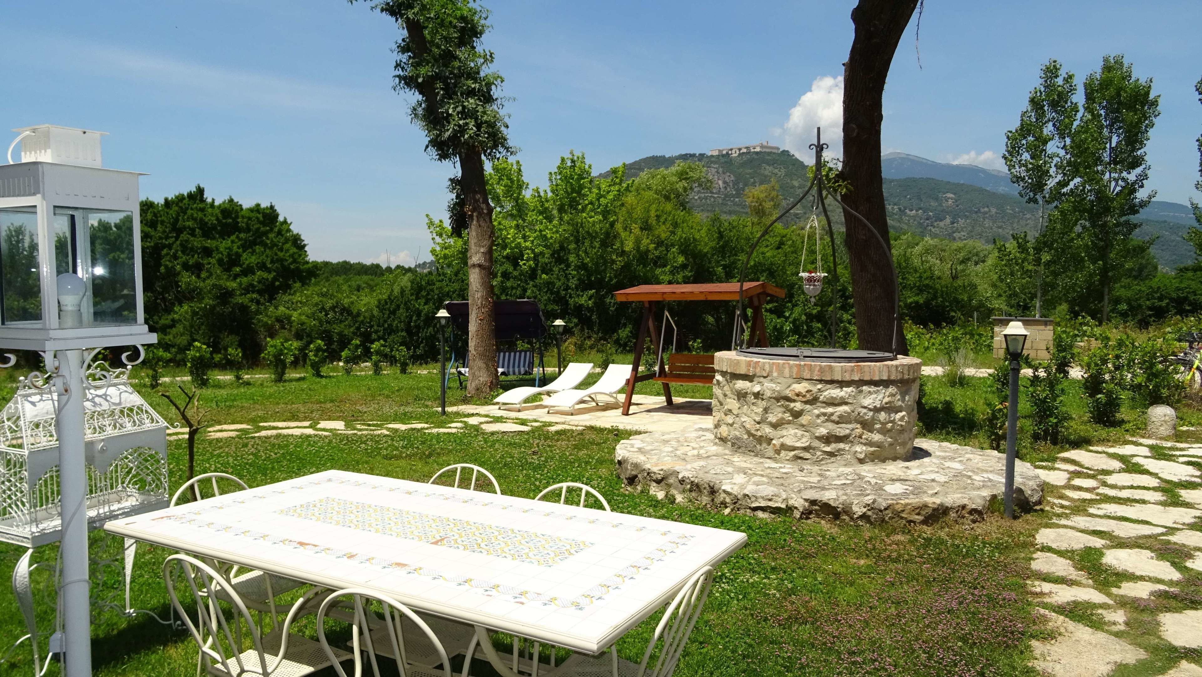An outdoor seating area with a table and chairs, a swing, and a stone structure.