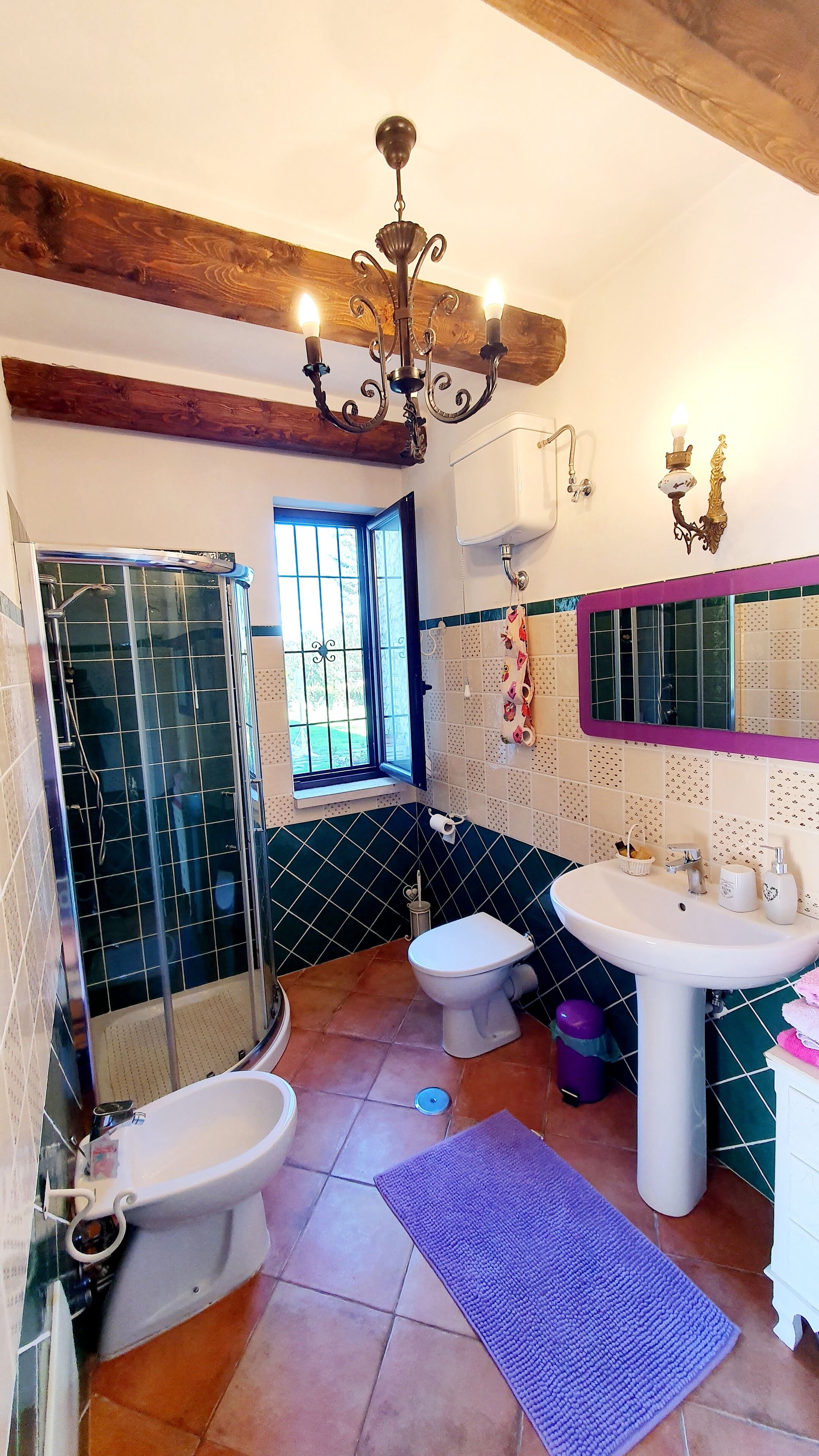 Ein Badezimmer mit Dusche, zwei Toiletten, einem Waschbecken und einer Chandelier.