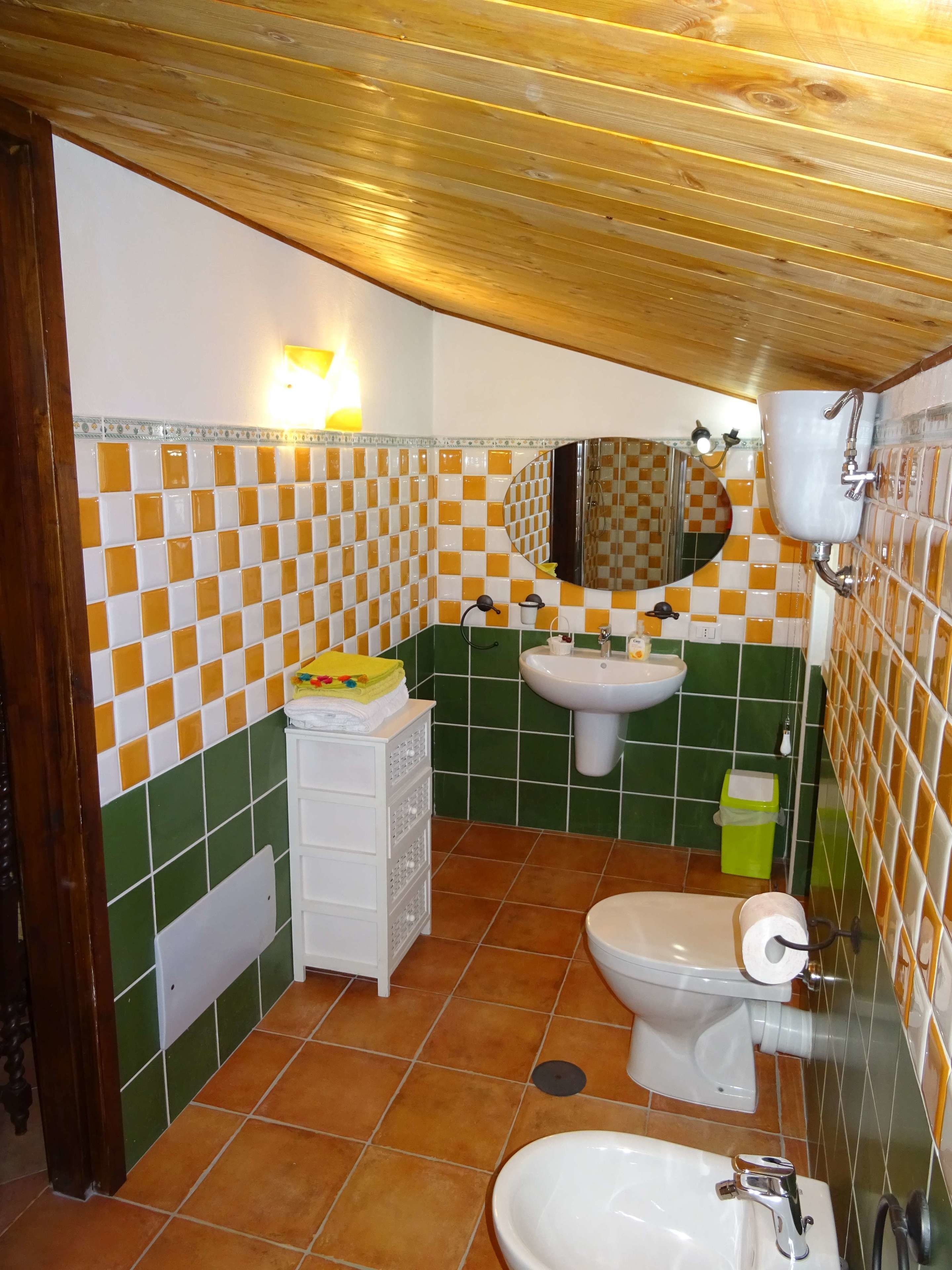 A bathroom with a checkered tile wall, a sink, a toilet, and a mirror.