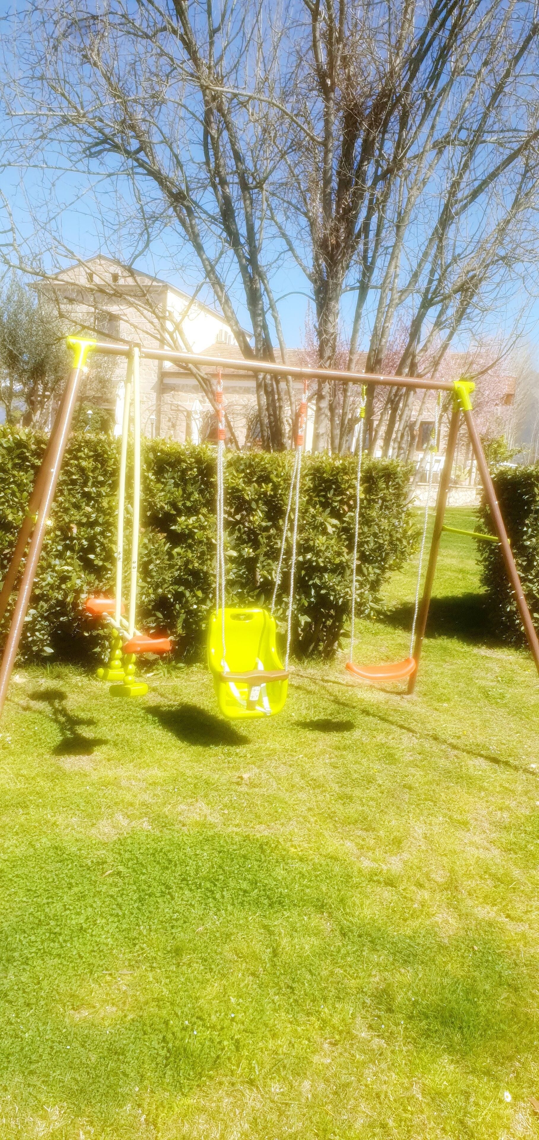 A swing set in a grassy yard with a house in the background.