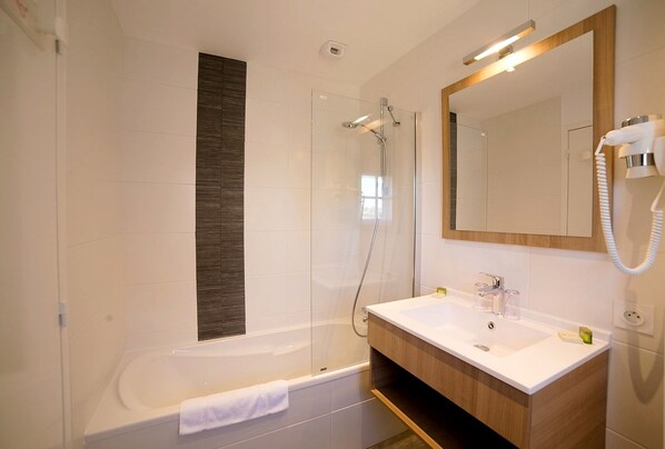 Un baño moderno con una bañera, ducha, tocador con espejo y teléfono.