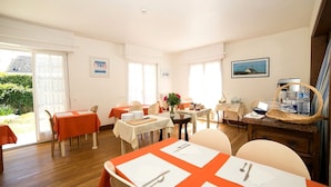 A dining area with tables set for four, a buffet station, and a view of the outdoors. - Hôtel An Ti Gwenn (Carnac)