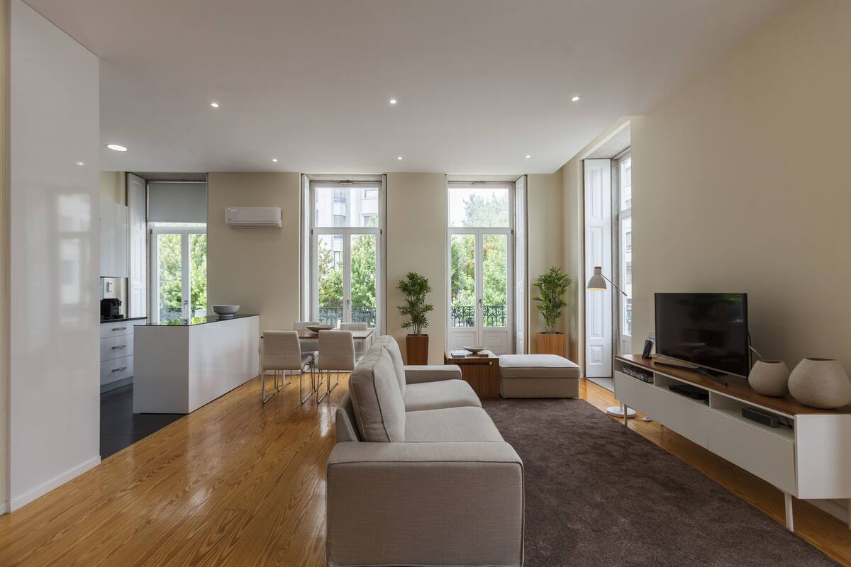 A modern living room with a sofa, a TV, and a kitchen area with a dining table.