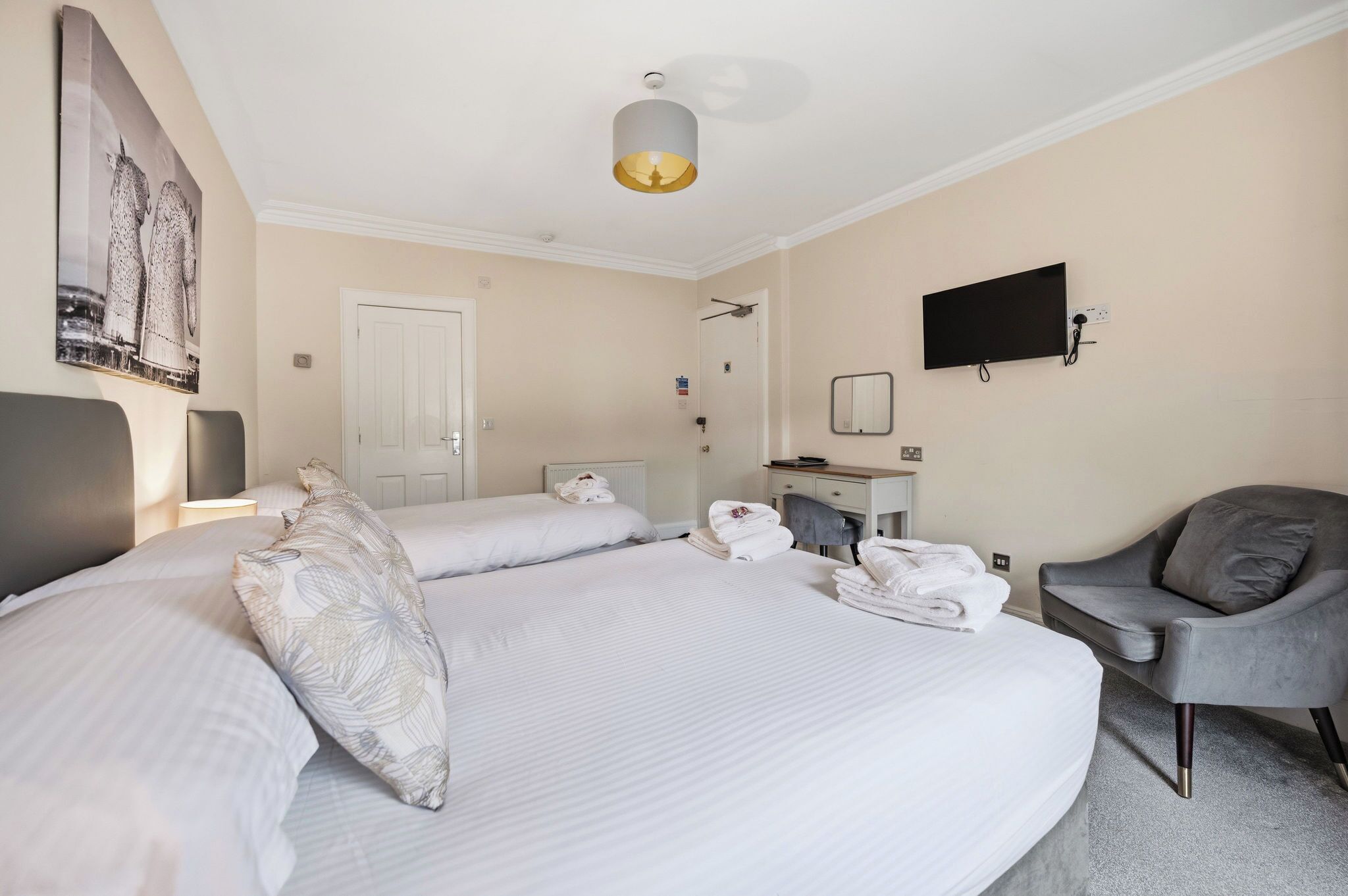 Una habitación de hotel con una cama, una silla, un escritorio, un televisor y una ducha.
